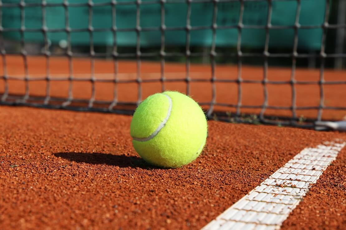 Ball liegt auf dem Hartplatz, Netz im Hintergrund